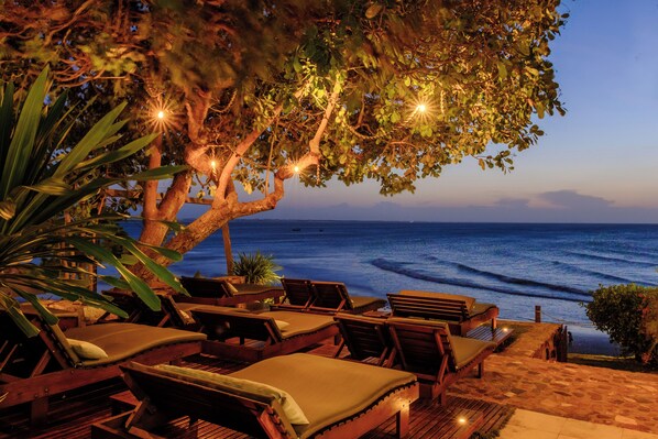 A wooden deck with lounge chairs and a tree providing shade. - Pousada Jeribá (Jijoca de Jericoacoara)