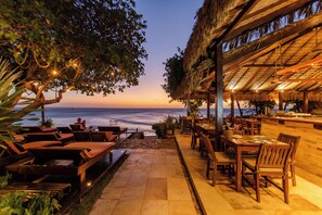 An outdoor dining area with a view of the ocean, wooden furniture, and a thatched-roof structure. - Pousada Jeribá (Jijoca de Jericoacoara)