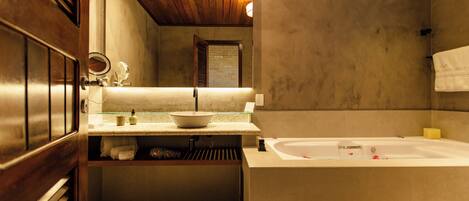 A bathroom with a bathtub, a sink with a bowl, a mirror, and a towel rack.