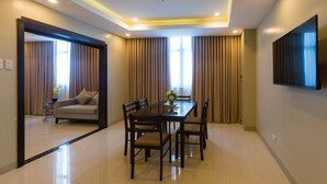 A modern dining area with a glass-top table, six wooden chairs, and a flat-screen TV mounted on the wall.