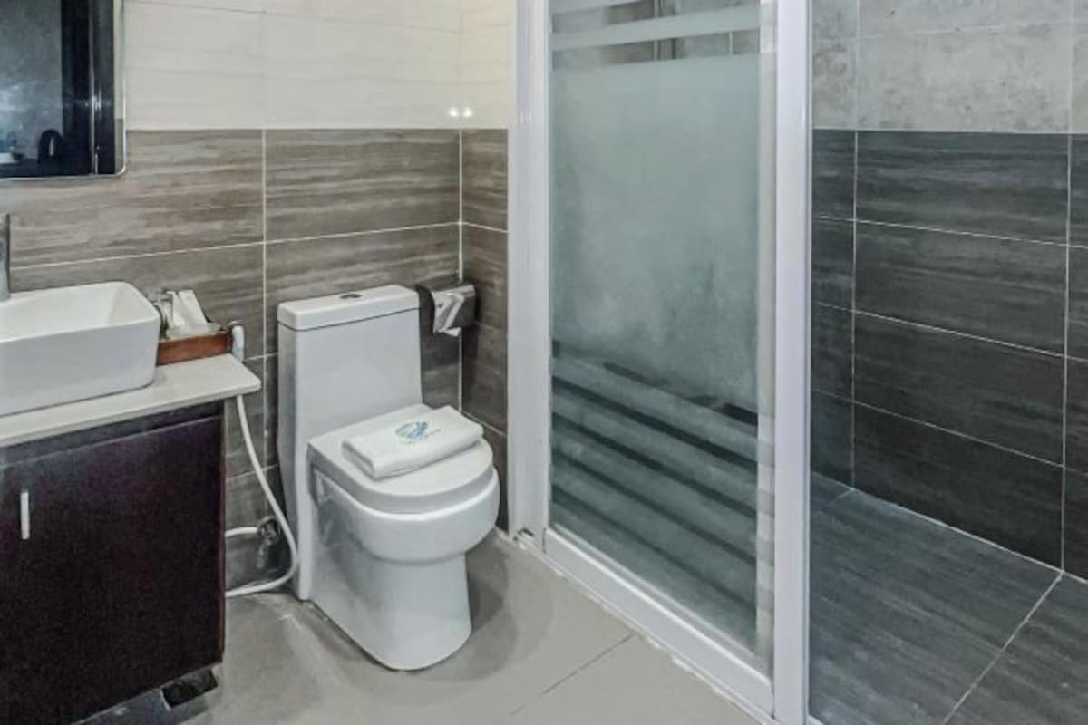 Un baño moderno con lavamanos blanco, inodoro y cabina de ducha de vidrio.