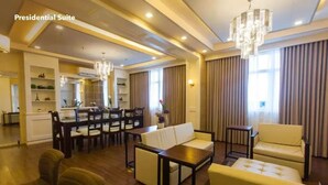 A spacious living area with a dining set, sofas, and a chandelier.