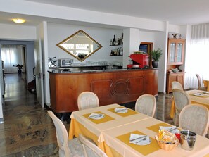 A dining area with a bar, tables set with yellow tablecloths, and chairs.