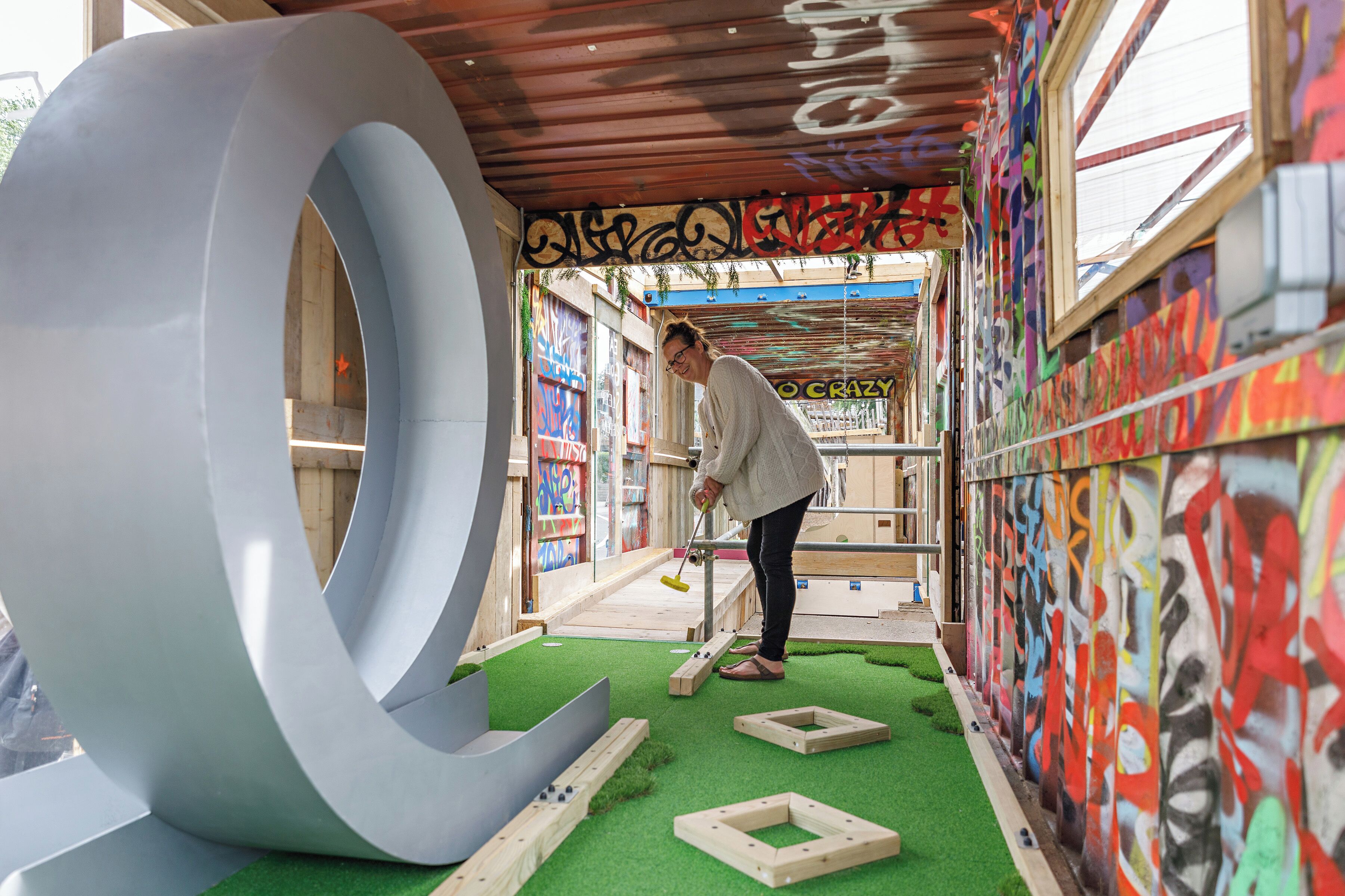 A person playing a game with wooden blocks and a large white ring structure.