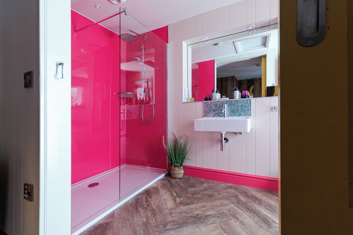 Une salle de bain moderne avec une douche à l’italienne en verre, un lavabo blanc et un miroir au-dessus.