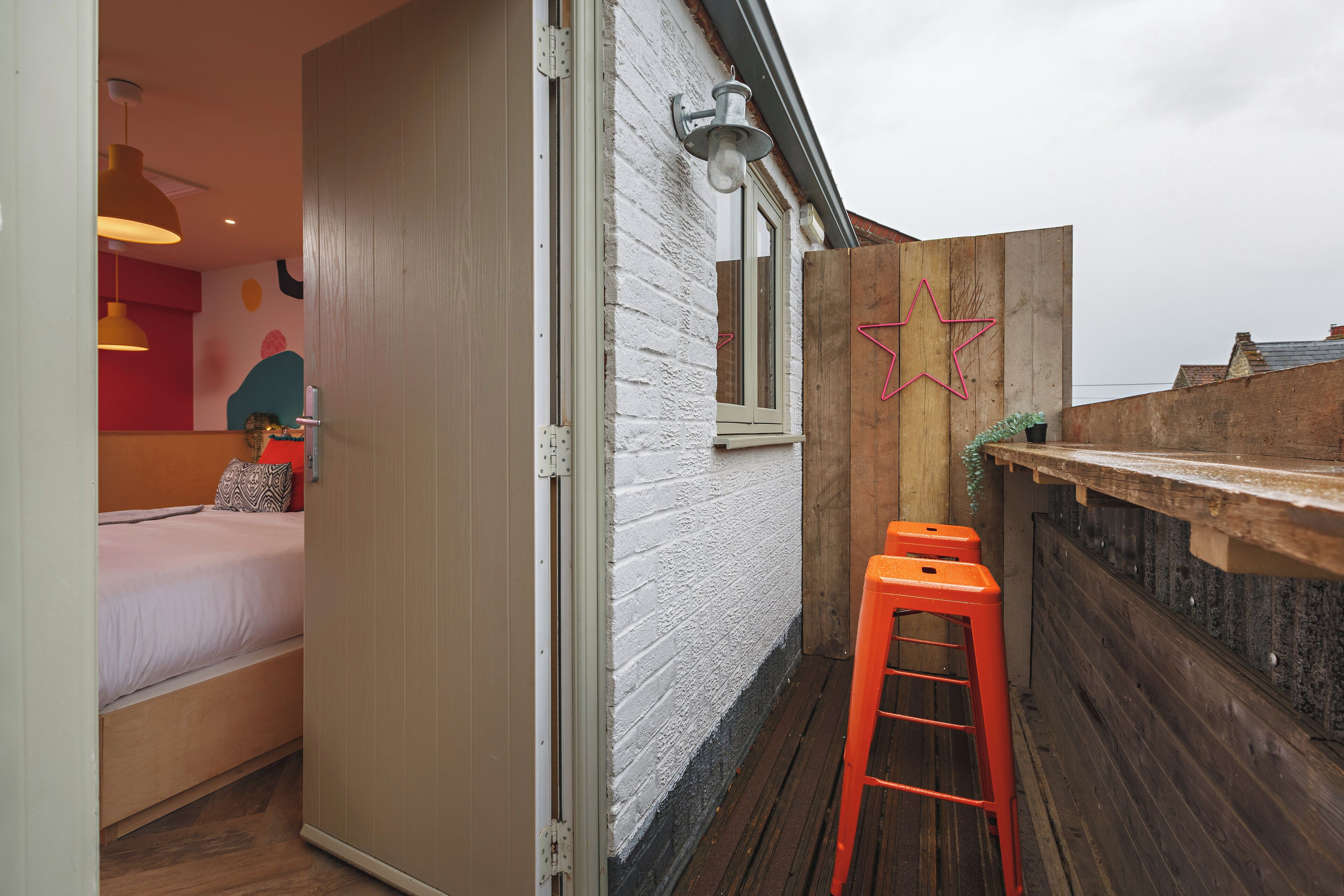 A compact room with a bed, a wooden stool, a white brick wall, and a star-shaped decoration.