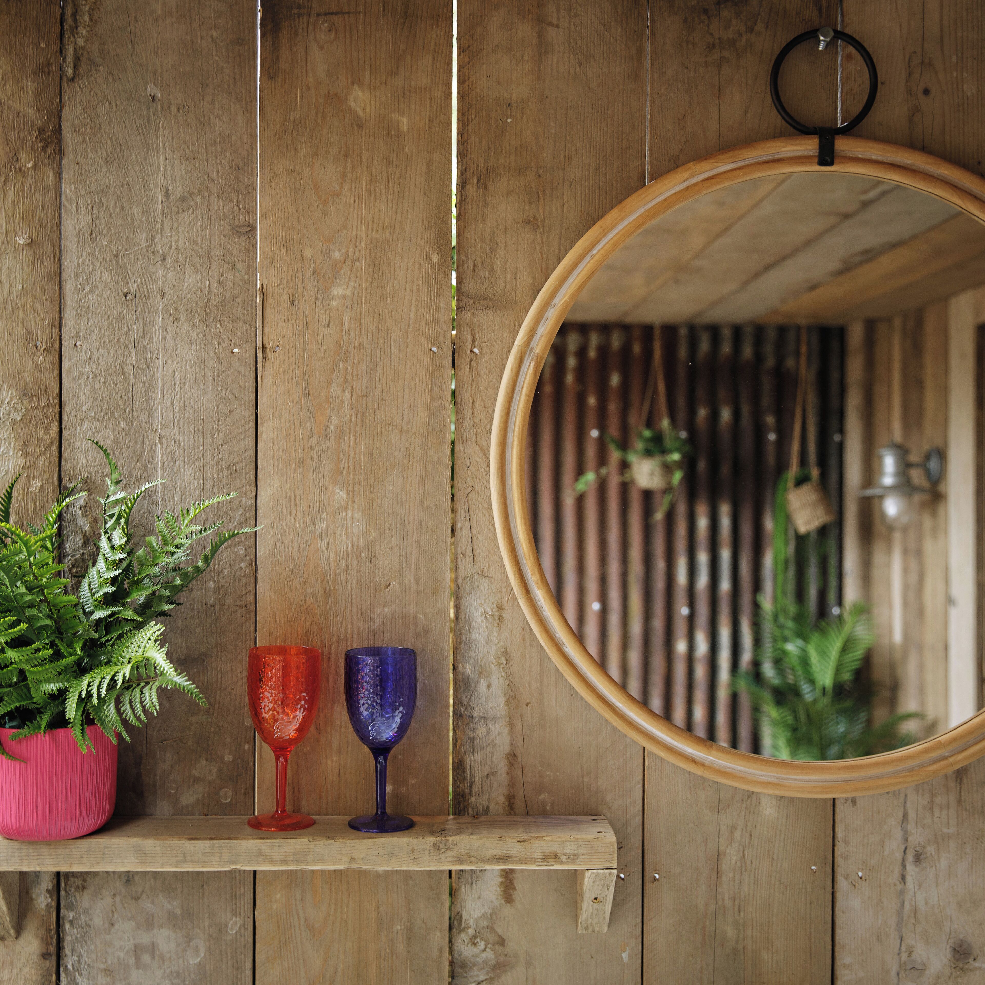 A wooden shelf with a potted plant and two glass vases.