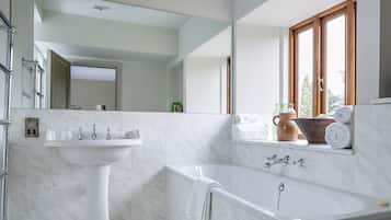 Un baño moderno con lavabo blanco, bañera y espejo grande.
