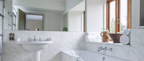 A modern bathroom with a white sink, bathtub, and large mirror.