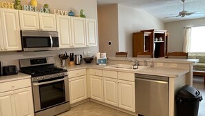 A kitchen with white cabinets, a microwave, stove, sink, and dishwasher.