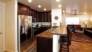 A modern kitchen with dark wood cabinets, stainless steel appliances, and a central island with bar stools.