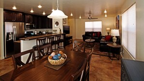 A modern kitchen with dark wood cabinets, stainless steel appliances, and a central island with bar stools.