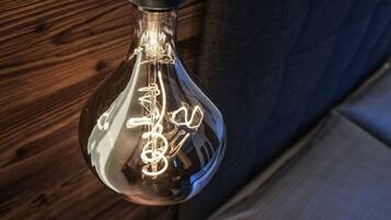 Un luminaire suspendu doté d’un abat-jour en verre transparent et dont le filament est visible.