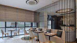 A modern interior with a seating area featuring sofas and tables, a decorative wall with vertical elements, and a view through large windows. - Gleam Bomonti Hotel (Istanbul)