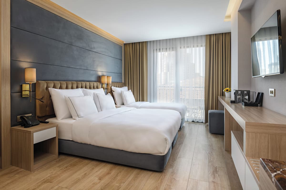 Una habitación de hotel moderna con una cama grande, lámparas de noche, un televisor y un escritorio con un espejo.