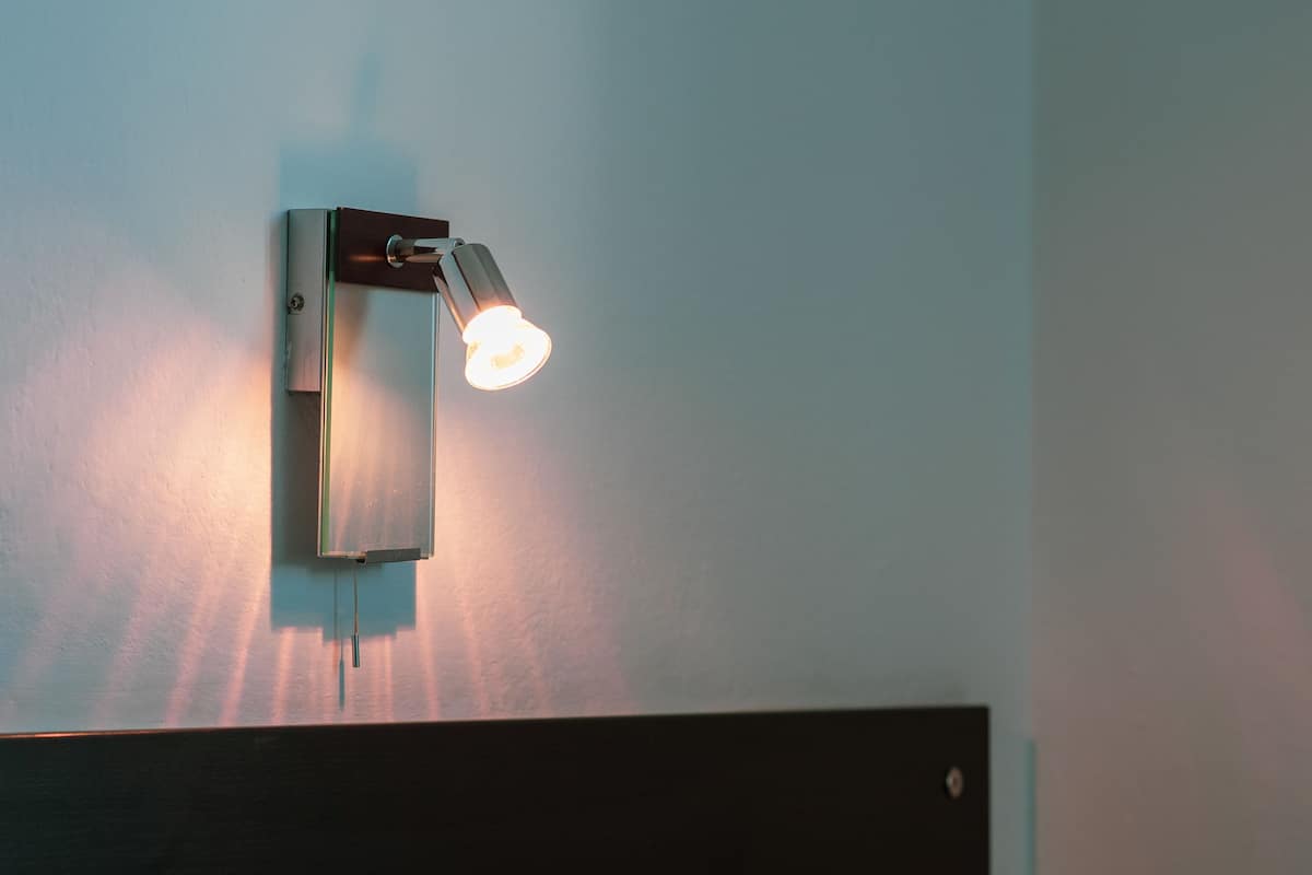 A bed with a headboard and a wall-mounted light fixture.