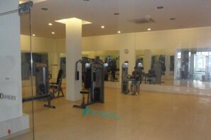 Ein Fitnessstudio mit Trainingsgeräten und Spiegeln an den Wänden.