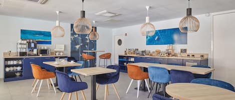 A modern cafe with multiple seating areas, including tables and chairs, and a counter with a coffee machine.
