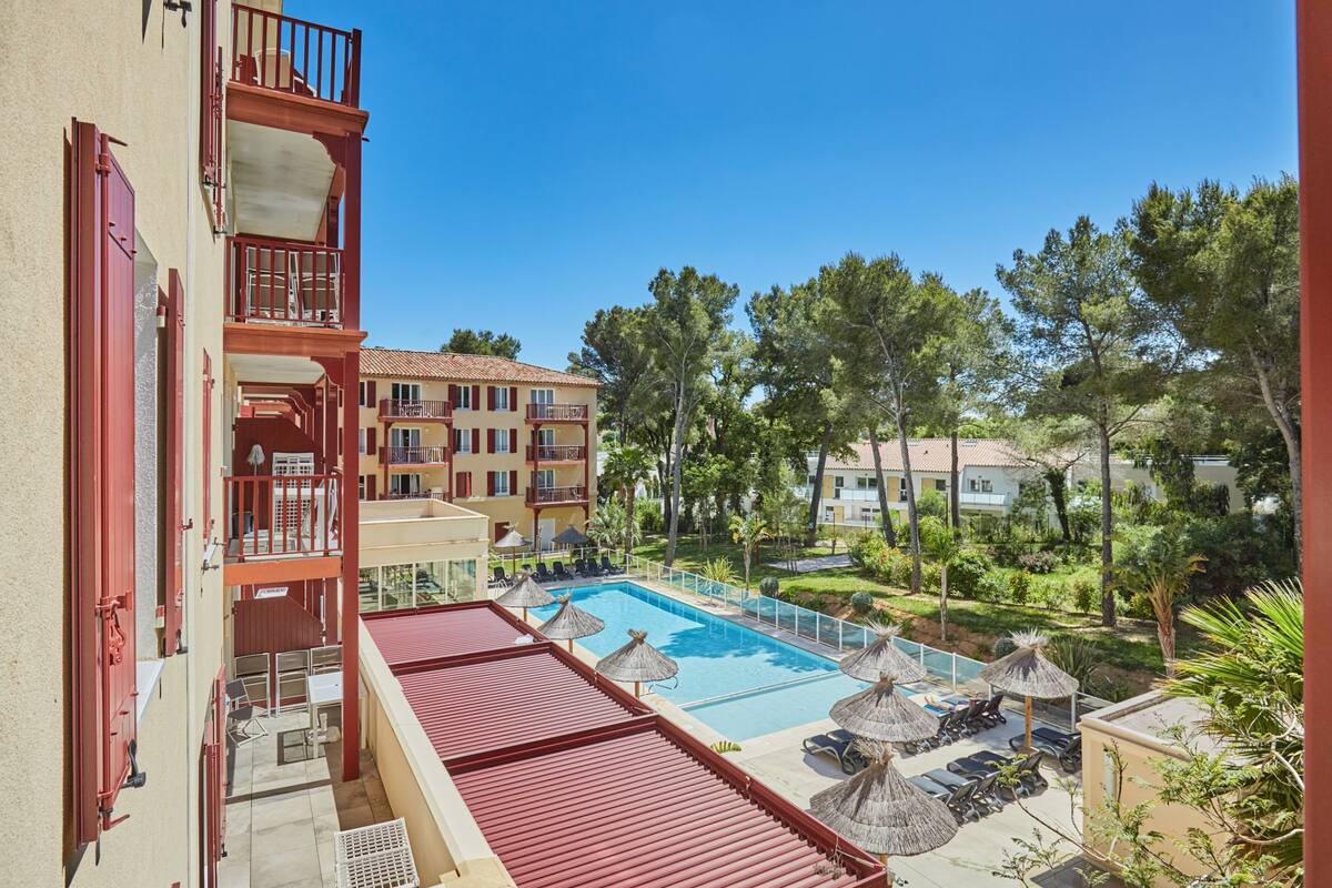 Ein Hotel mit Schwimmbad, Außenbereich und Blick auf die grüne Umgebung.