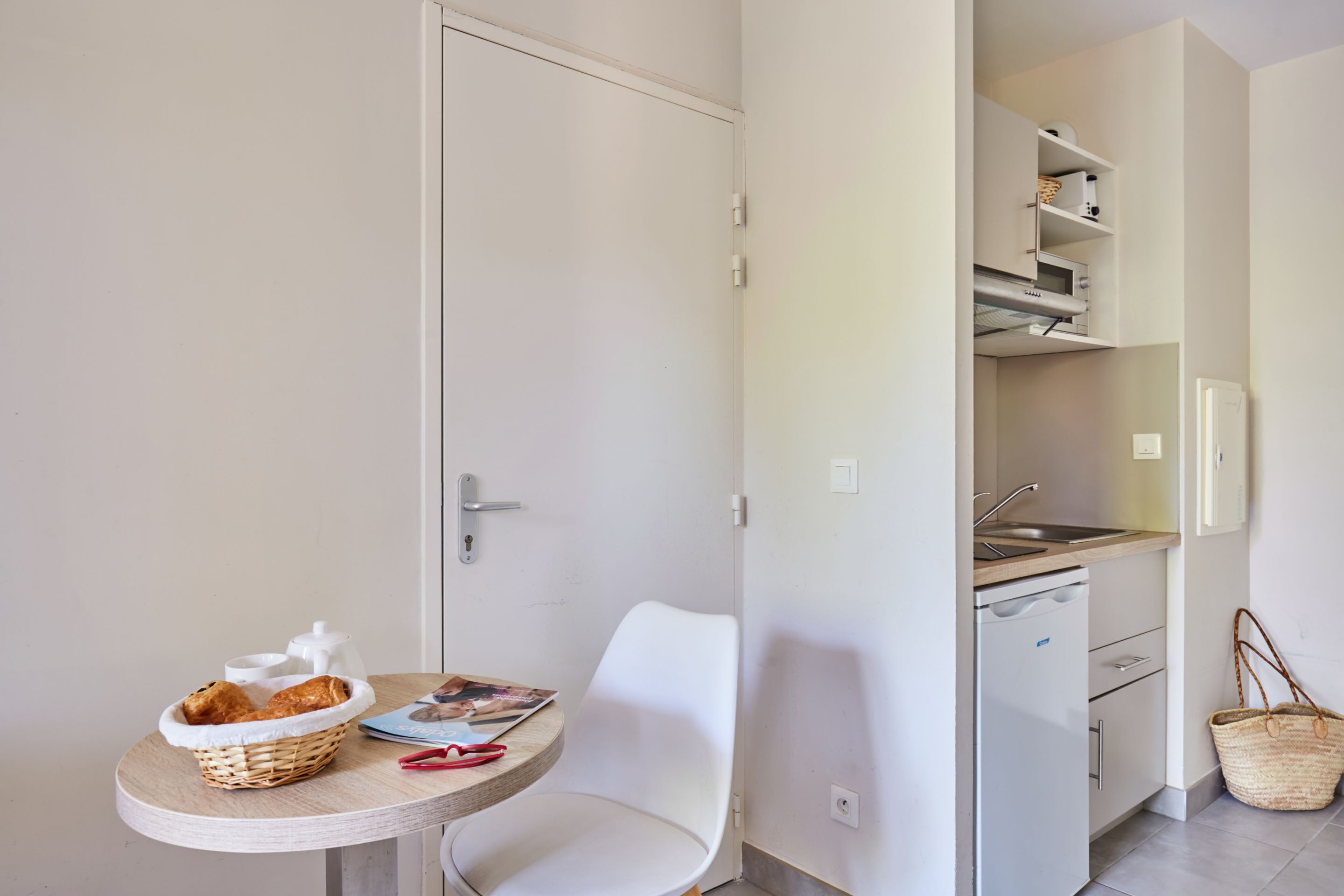 A compact kitchen with a sink, cabinets, and a small dining area with a table and chair.