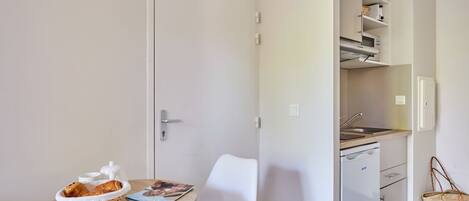 A compact kitchen with a sink, cabinets, and a small dining area with a table and chair.