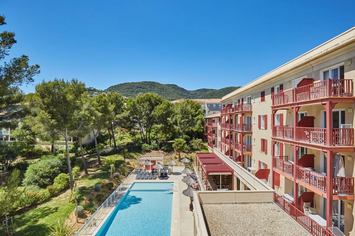 Ein Hotel mit Schwimmbad, Außenbereich und Blick auf die umliegende Natur und Hügel.