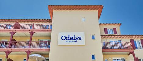 A building with balconies and a sign that reads "Odalys Vacances."