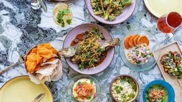 A variety of dishes on a marble table, including a whole fish, bowls of salad, and other food items.