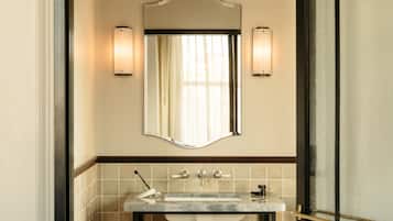 A bathroom with a large mirror, two wall-mounted lights, a marble sink, and a towel rack.