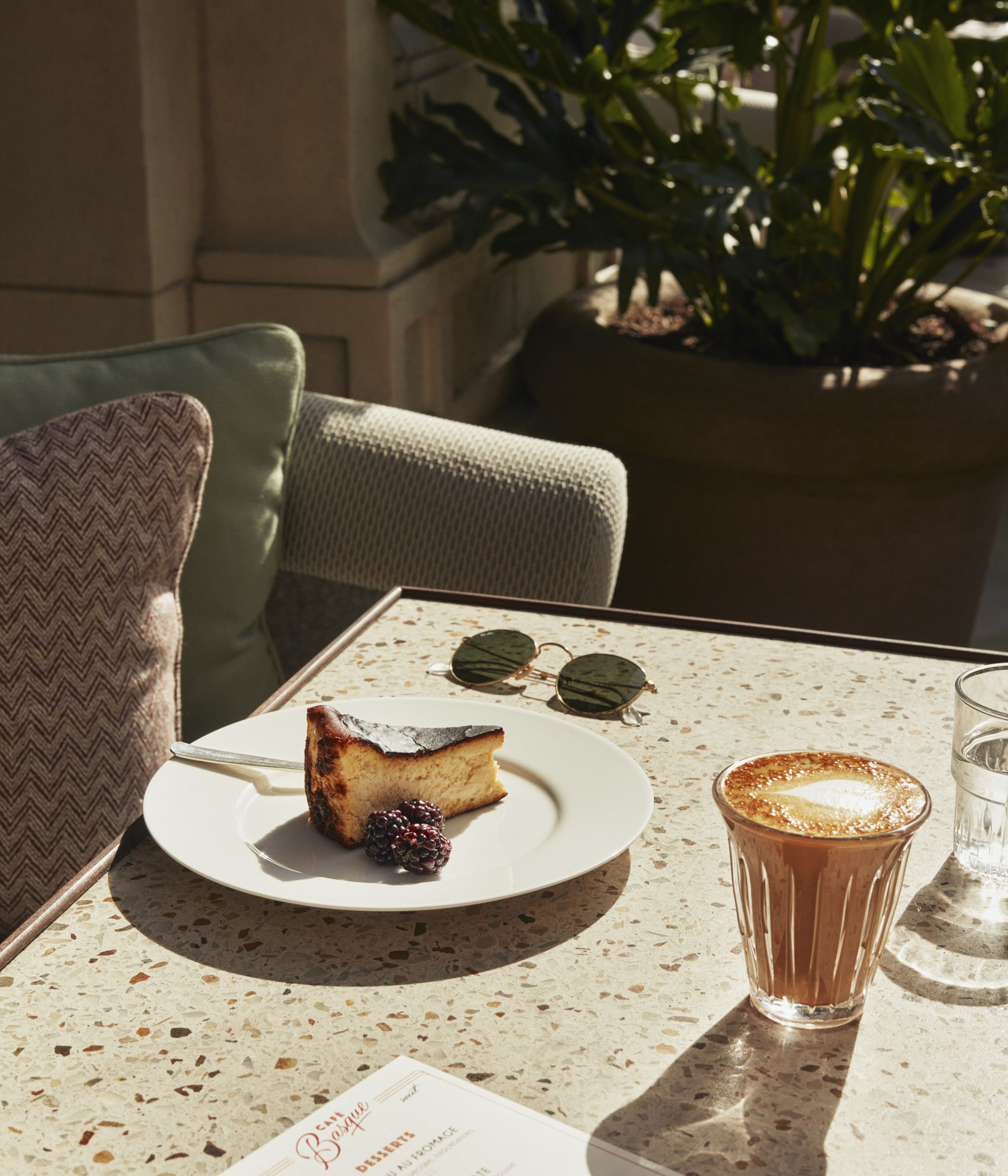 Uma mesa com uma fatia de bolo, um copo de café e um cardápio.