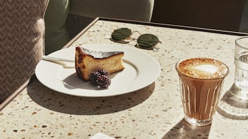 Uma mesa com uma fatia de bolo, um copo de café e um cardápio.