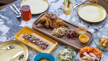 Ein Tisch reichhaltig gedeckt mit verschiedenen Gerichten, darunter Brathähnchen, Reis und Salaten, was auf eine Mahlzeit hindeutet.