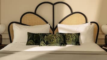 A bed with a rattan headboard, white pillows, and a green patterned pillow.