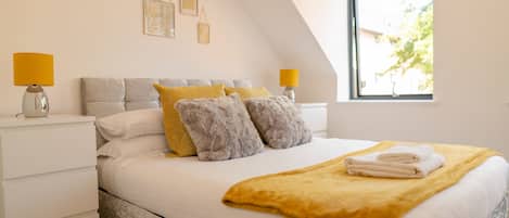 A bedroom with a bed, two bedside lamps, a window, and a view of the outdoors.