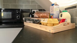 Eine Küchenarbeitsplatte mit einer Mikrowelle, einem Brotlaib, einer Milchpackung, einer Orangensaftpackung und einem Holzschnittbrett.