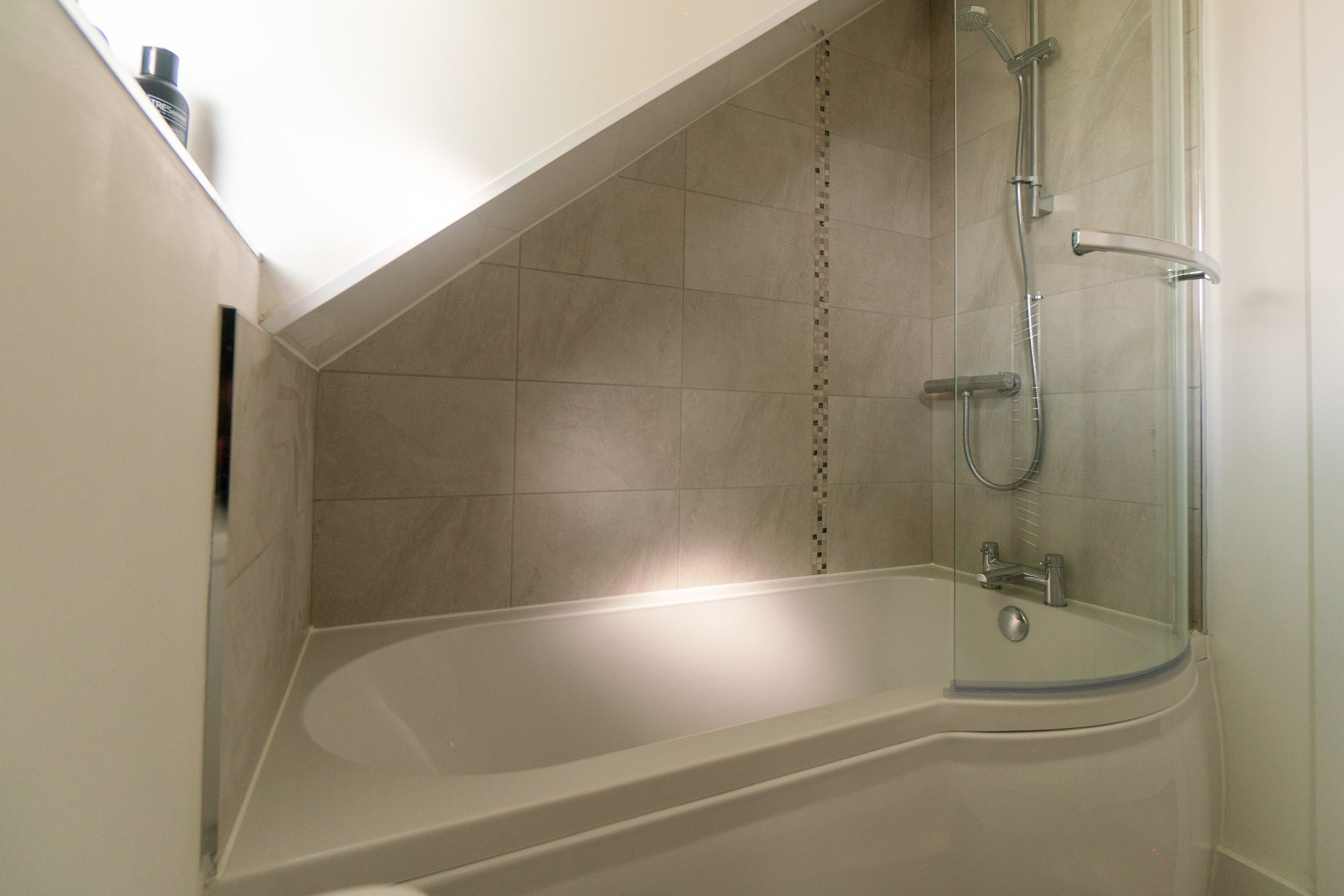 Een moderne badkamer met een vrijstaand bad, een douchecabine met glazen wanden en betegelde muren.