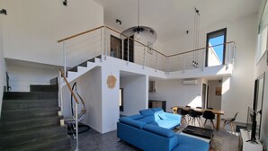 A modern interior with a staircase, a blue sofa, and a dining area. - Architect-designed villa, secure private pool, near center and beach  (Calvi)