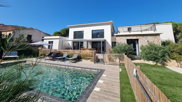 A modern two-story house with a swimming pool, outdoor seating, and a stone facade. - Architect-designed villa, secure private pool, near center and beach  (Calvi)