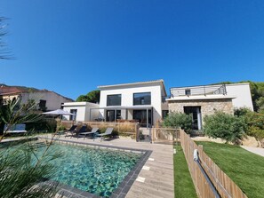 A modern two-story house with a swimming pool, outdoor seating, and a stone facade. - Architect-designed villa, secure private pool, near center and beach (Calvi)