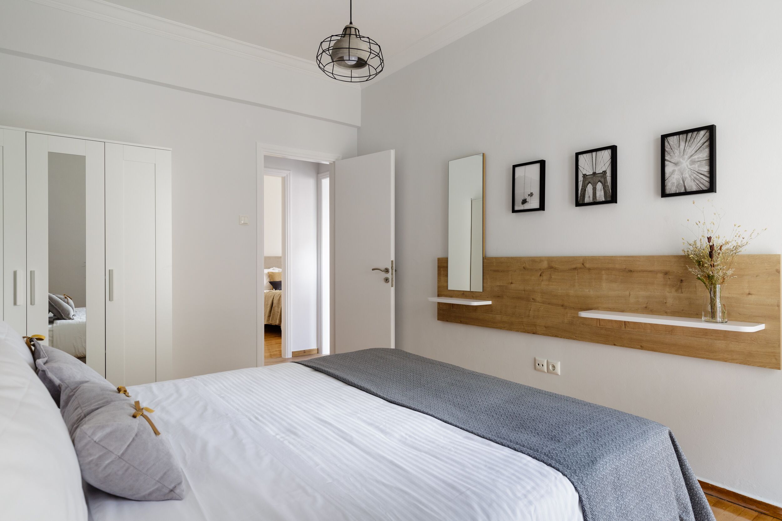 Un dormitorio moderno con cama, armario blanco y cabecera de madera.
