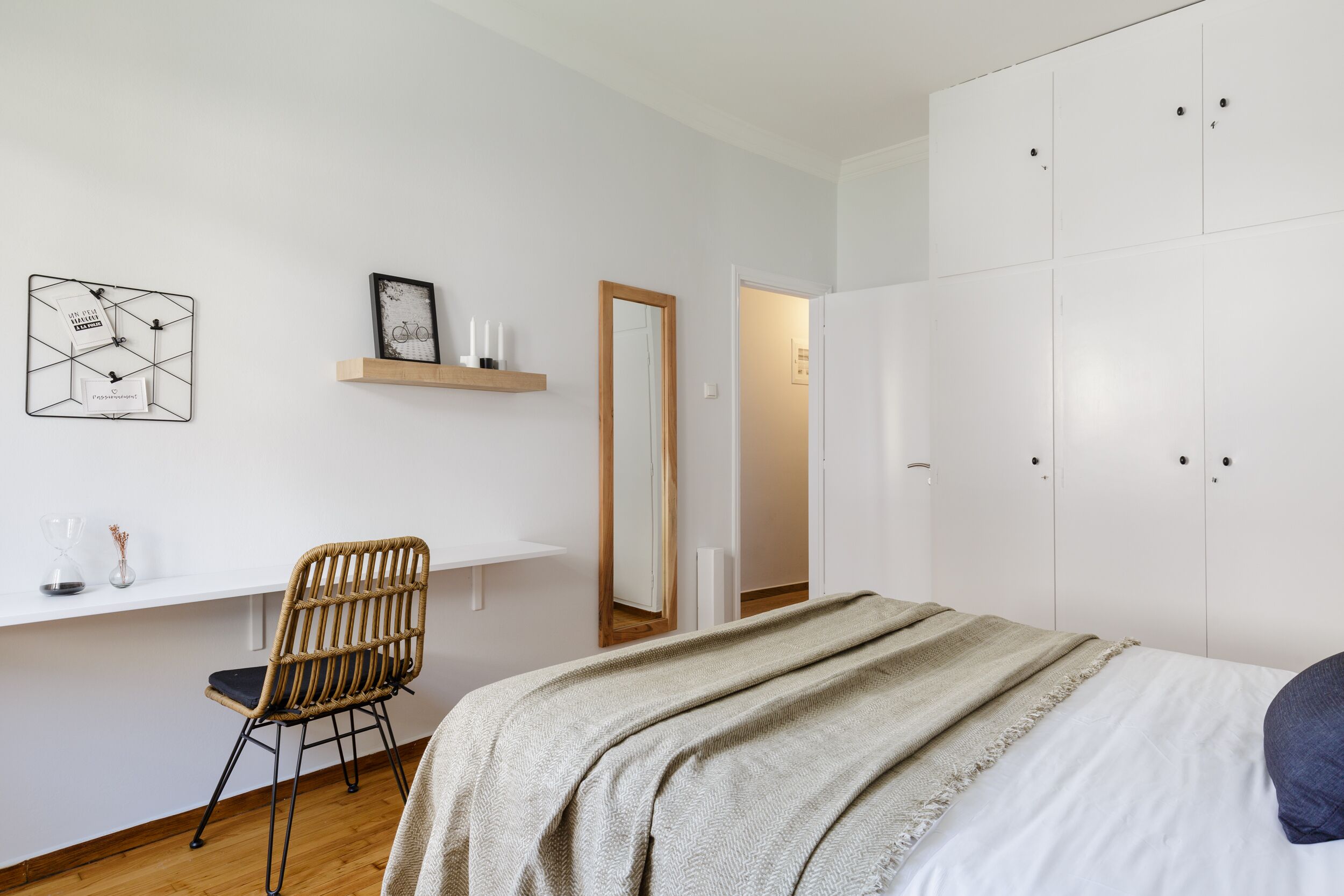 A bedroom with a bed, a chair, a desk, a wardrobe, and a mirror.