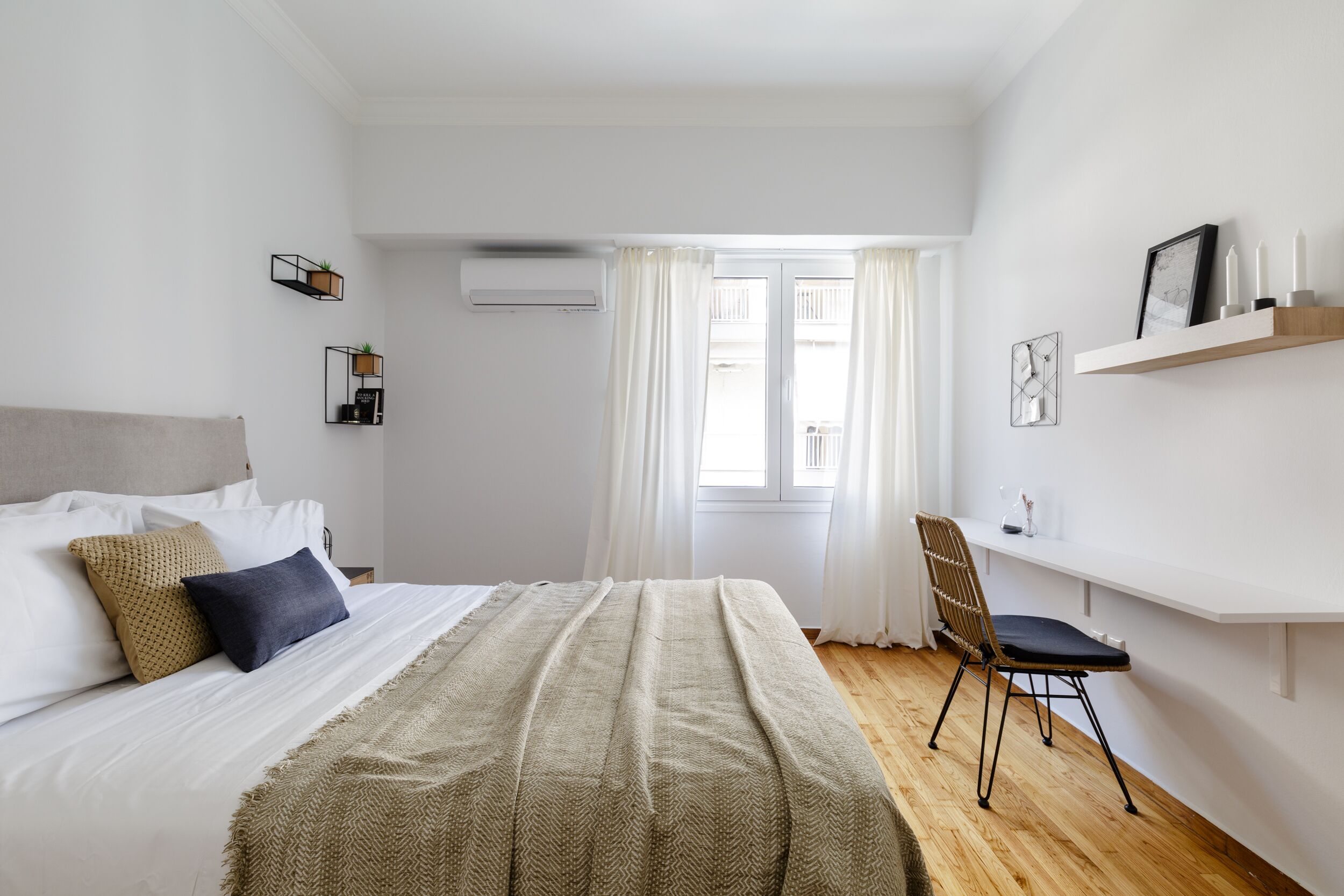 A bedroom with a bed, a chair, a shelf with candles, and a window with curtains.
