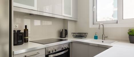 A modern kitchen with a built-in oven, a kettle, and a coffee maker.
