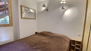 A bedroom with a bed, a window, a radiator, and wall-mounted lights. - 150m from ski slopes, floor -2, view mountain, balcony, 37m², Méribel-Mottaret (Méribel - Les Allues)