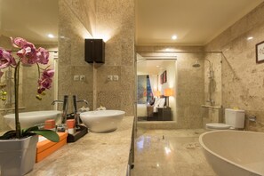 Een moderne badkamer met een ruime badkuip, een douche met glazen wanden en een wastafelmeubel met twee wastafels.