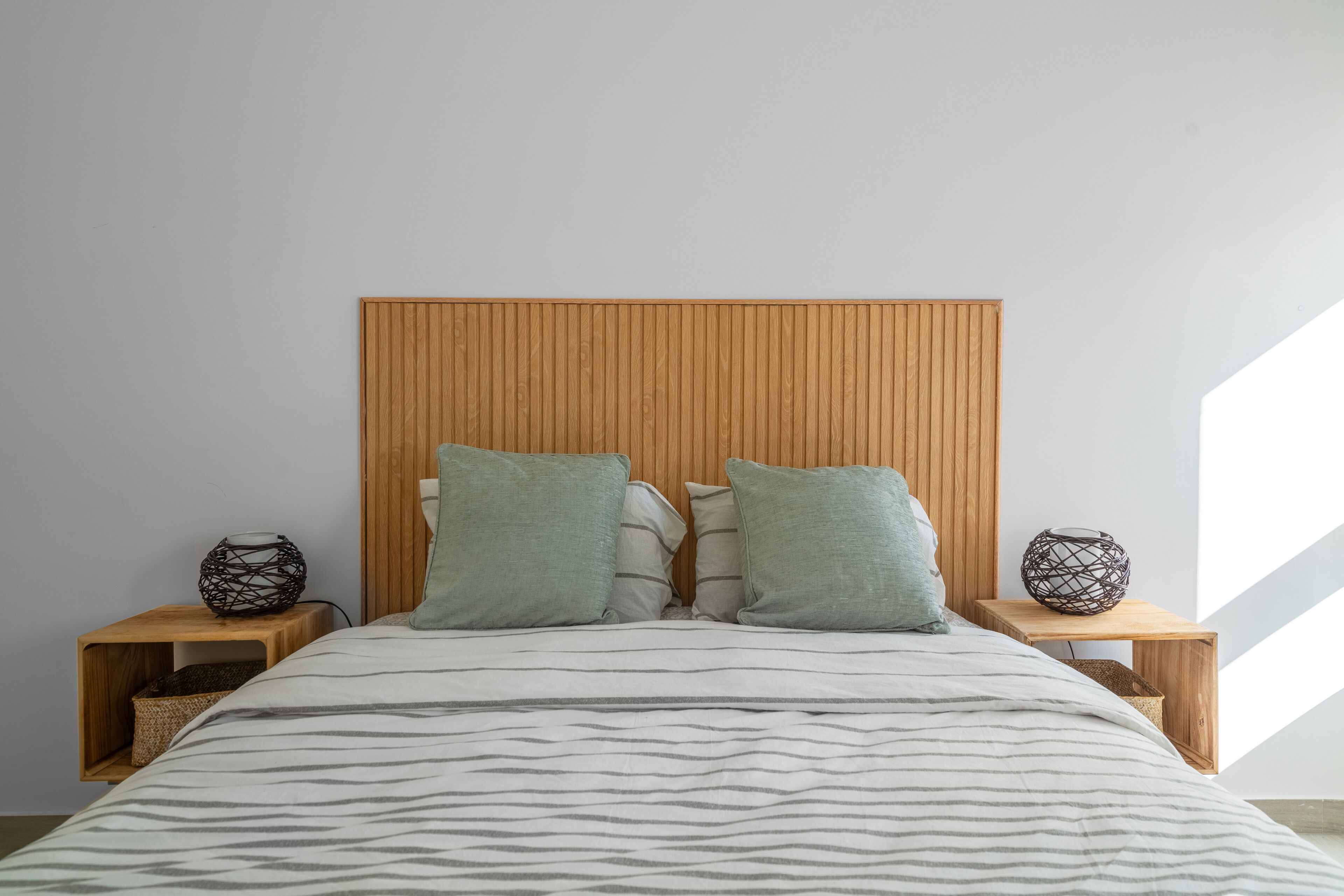 A bedroom with a wooden headboard, two nightstands, and a bed with striped bedding.