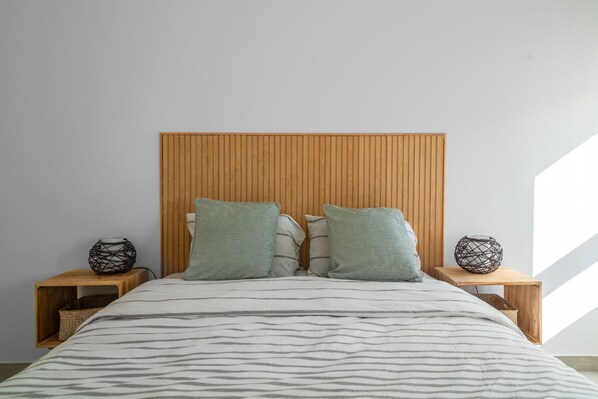 A bedroom with a wooden headboard, two nightstands, and a bed with striped bedding. - Amazing sea view from the balcony and bedroom. H (Armação de Pêra)