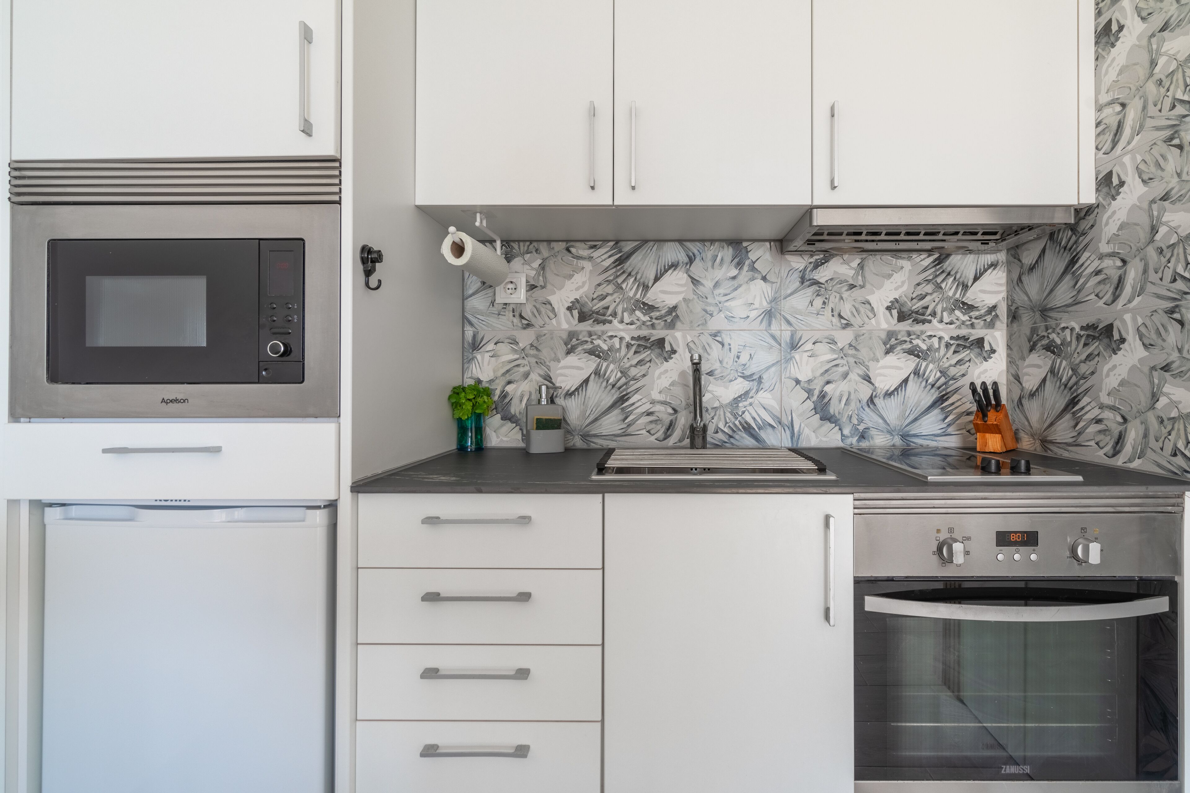 A modern kitchen with a built-in microwave, oven, and sink.