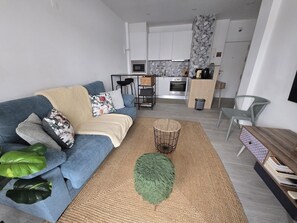 A modern living room with a blue sofa, a coffee table, and a kitchen in the background. - Amazing sea view from the balcony and bedroom. H (Armação de Pêra)
