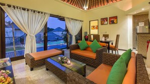 A spacious living area with wicker furniture, a glass coffee table, and a view of a swimming pool. - 2 Bedroom villa near Pandawa Beach (Uluwatu)
